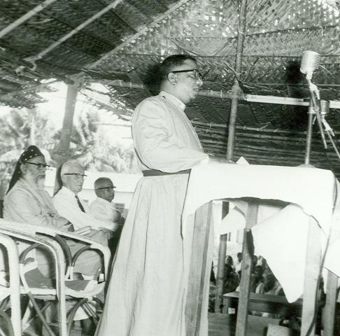 Bishop T. S. Joseph speaking at the Maramon Convention while Bishop Alexander Mar Theophilus (Metropolitan Alexander Mar Thoma), E. Stanley Jones and Mr. Ramenpillar listen.